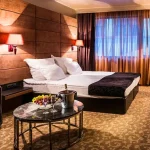 Delux dvokrevetna soba u Grand Hotelu Bansko predstavlja idealan izbor za parove i male porodice koje žele uživati u vrhunskom komforu. Ove sobe, površine oko 35 m², pružaju prostran i elegantan prostor za opuštanje i odmor. Svaka soba opremljena je francuskim ležajem ili dva singl kreveta, što omogućava fleksibilnost u smeštaju.